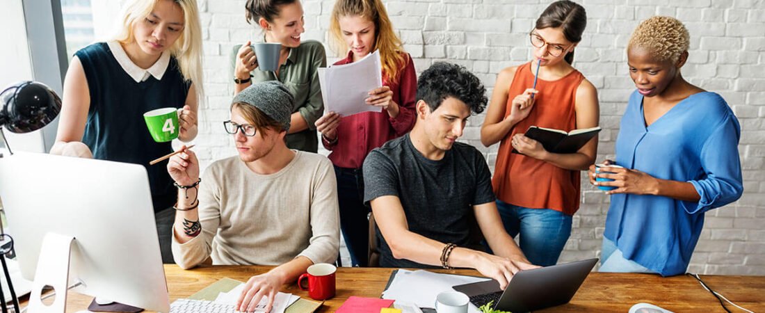 A team working together around a desk with laptops and notes
