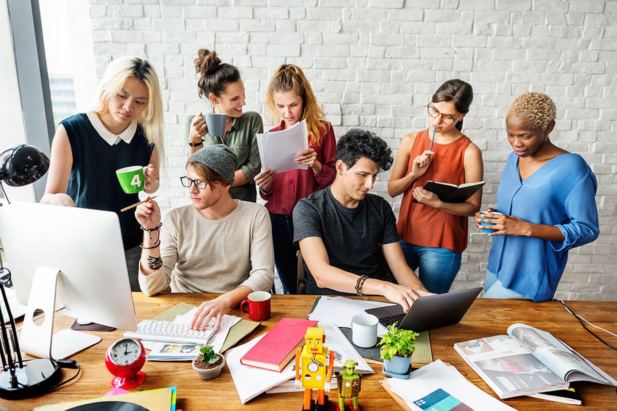 A team working together around a desk with laptops and notes