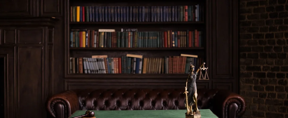 Law library with shelves of books and scales of justice on a desk
