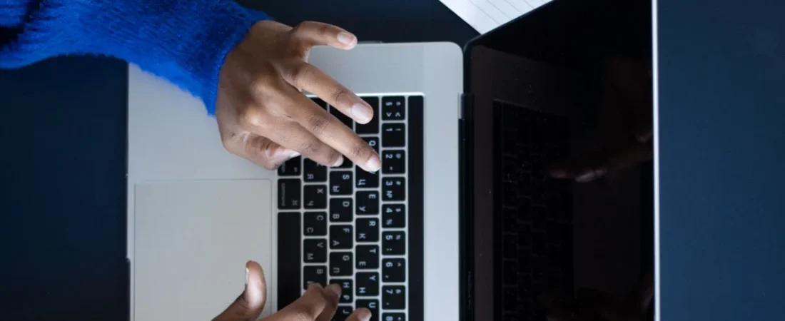 Writing law firm website content on a laptop beside a notebook