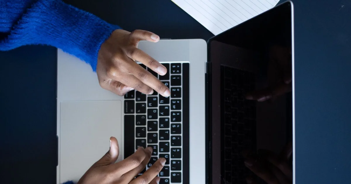 Writing law firm website content on a laptop beside a notebook