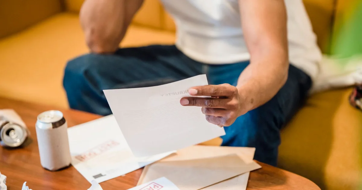 Man on a sofa reading unpaid bills