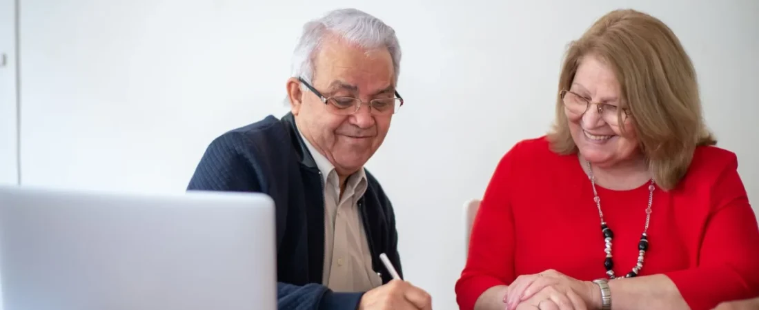 Older couple signing estate planning documents at a desk