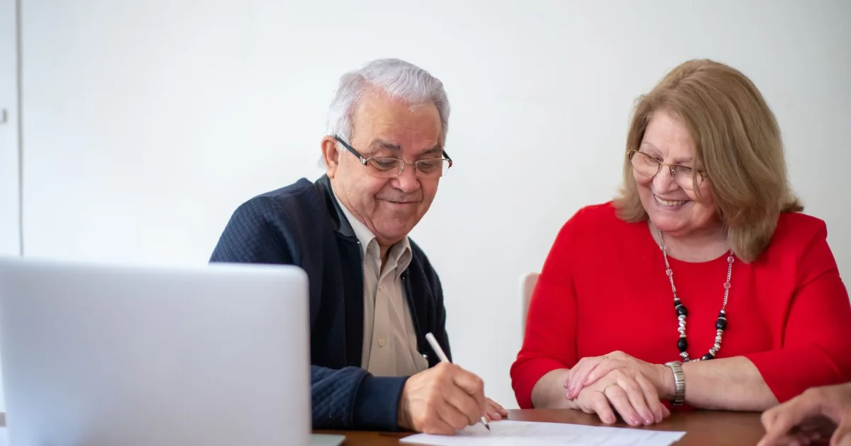 Older couple signing estate planning documents at a desk